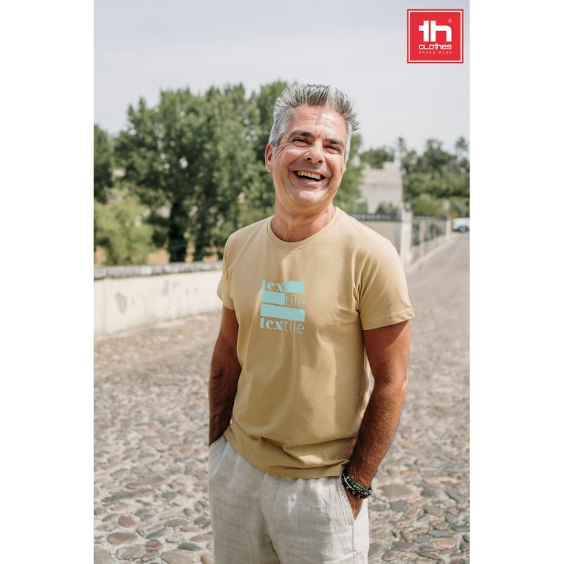 Smiling man in beige t-shirt outdoors.
