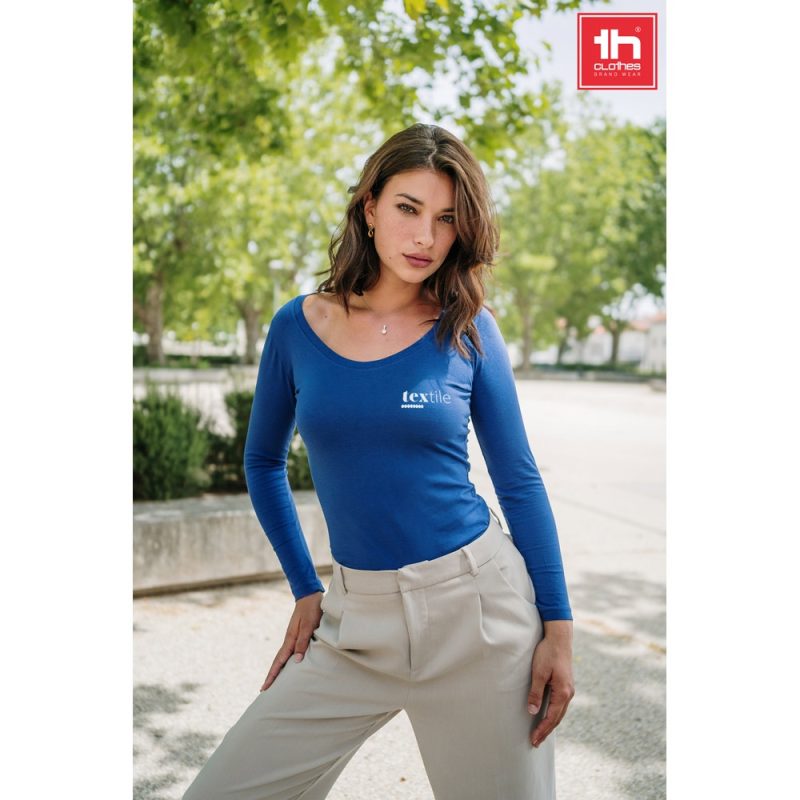 Woman in blue top outdoors, branding logo visible.