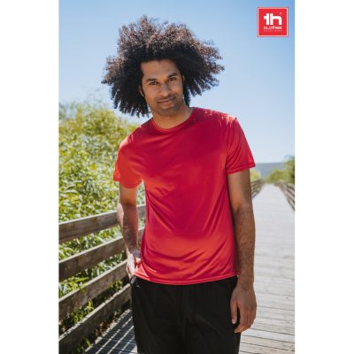 Person in red shirt standing on wooden walkway outdoors.