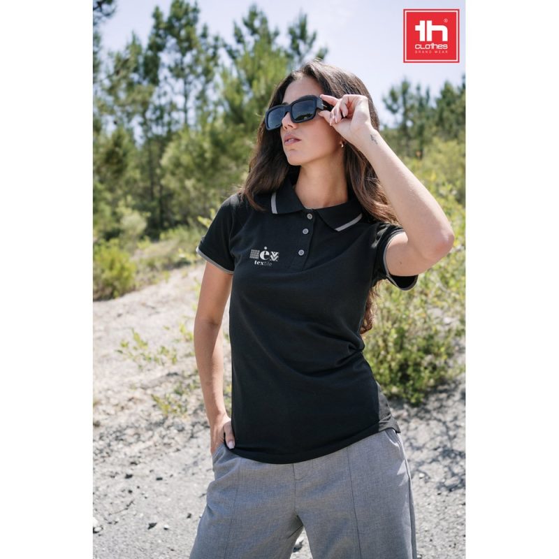 Woman wearing black polo shirt and sunglasses outdoors.