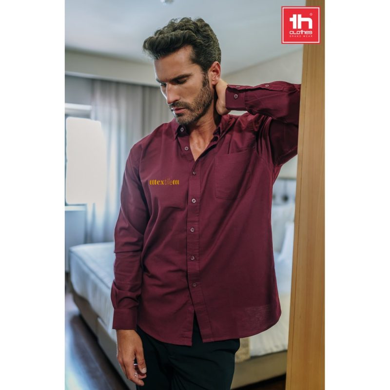 Man wearing maroon shirt in a bedroom.