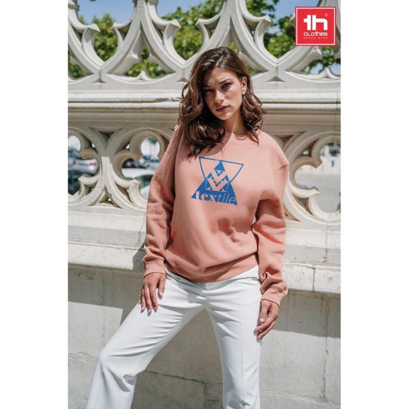 Woman wearing pink sweatshirt, outdoor fashion shot.