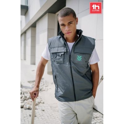 Man wearing grey work vest outdoors.