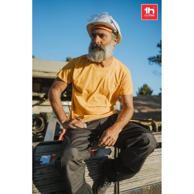 Worker in hard hat and yellow shirt outdoors.