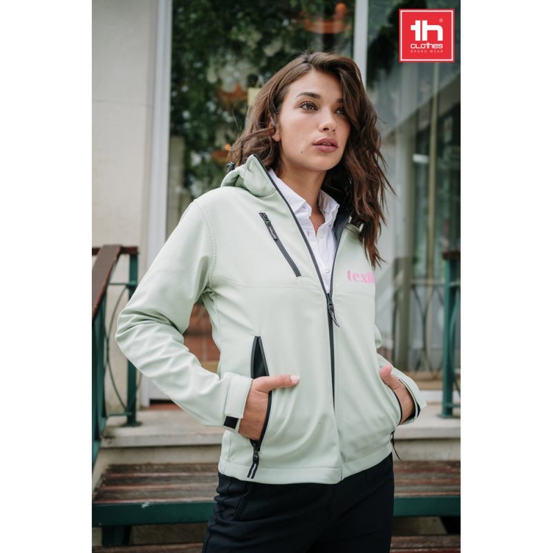 Woman wearing light green hooded jacket outdoors.