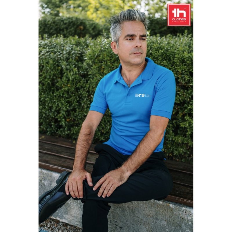 Man in blue polo shirt sitting outdoors.
