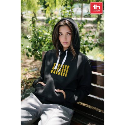 Person wearing black hoodie with yellow print outdoors.