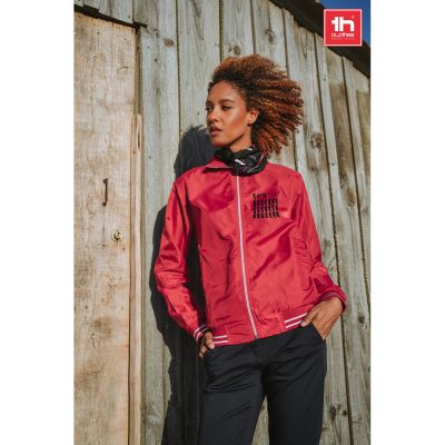 Model in red jacket against wooden wall.