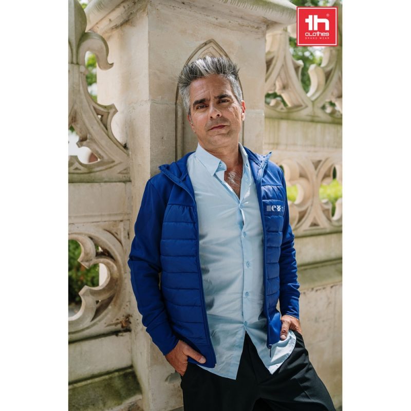 Man in a blue jacket against ornate stone wall.