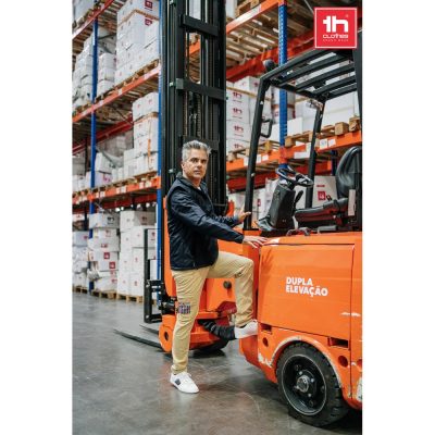 Man operating forklift in warehouse with stacked boxes.