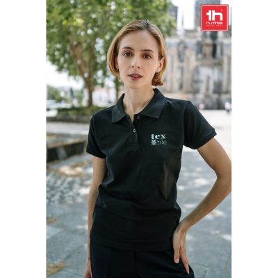 Woman in black polo shirt outdoors.