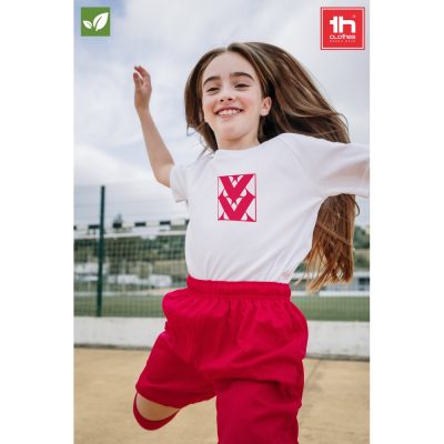 Girl jumping joyfully in sportswear outdoors.