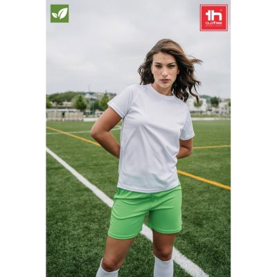 Woman in sportswear standing on football pitch.
