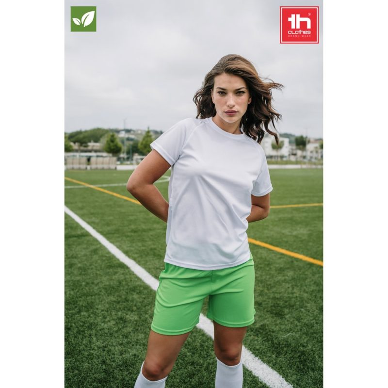 Woman in sportswear standing on football pitch.