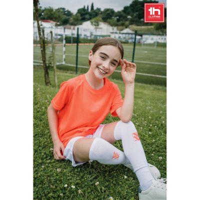 Smiling child in sportswear on grass field.