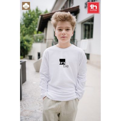Child wearing white 'textile' long sleeve top outdoors.