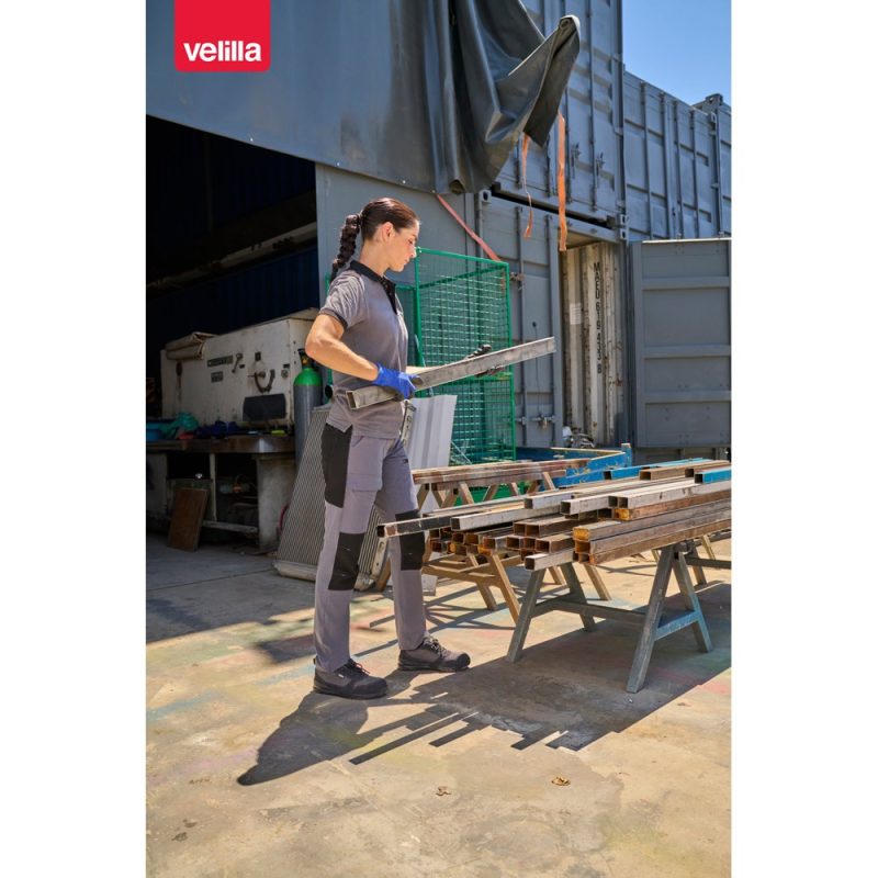 Person in workwear handling metal bars outdoors.
