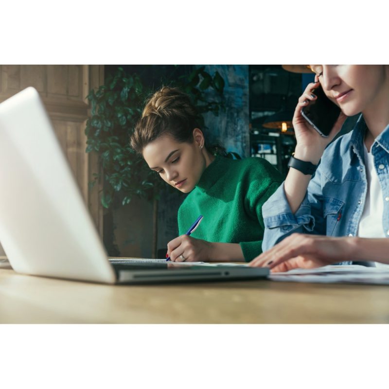 Women working at a laptop in a modern office.