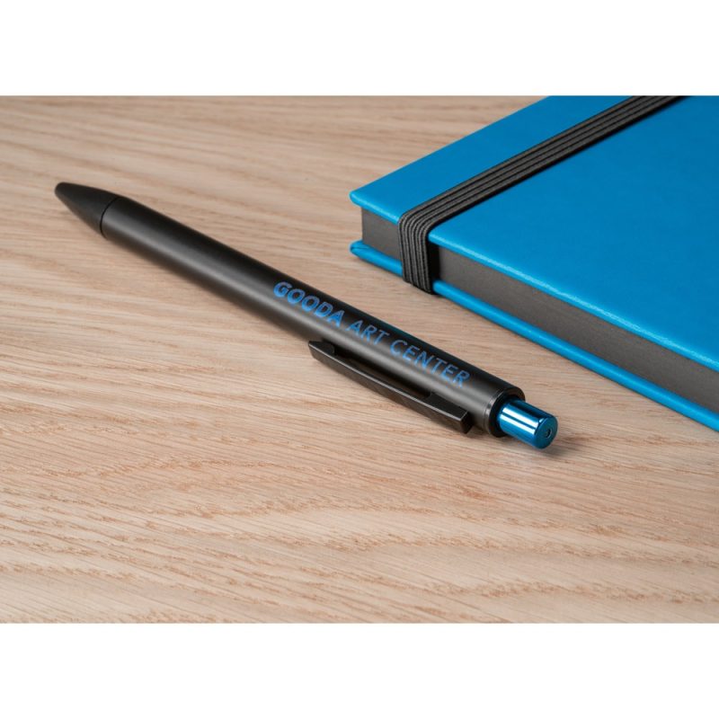 Black pen and blue notebook on wooden desk.