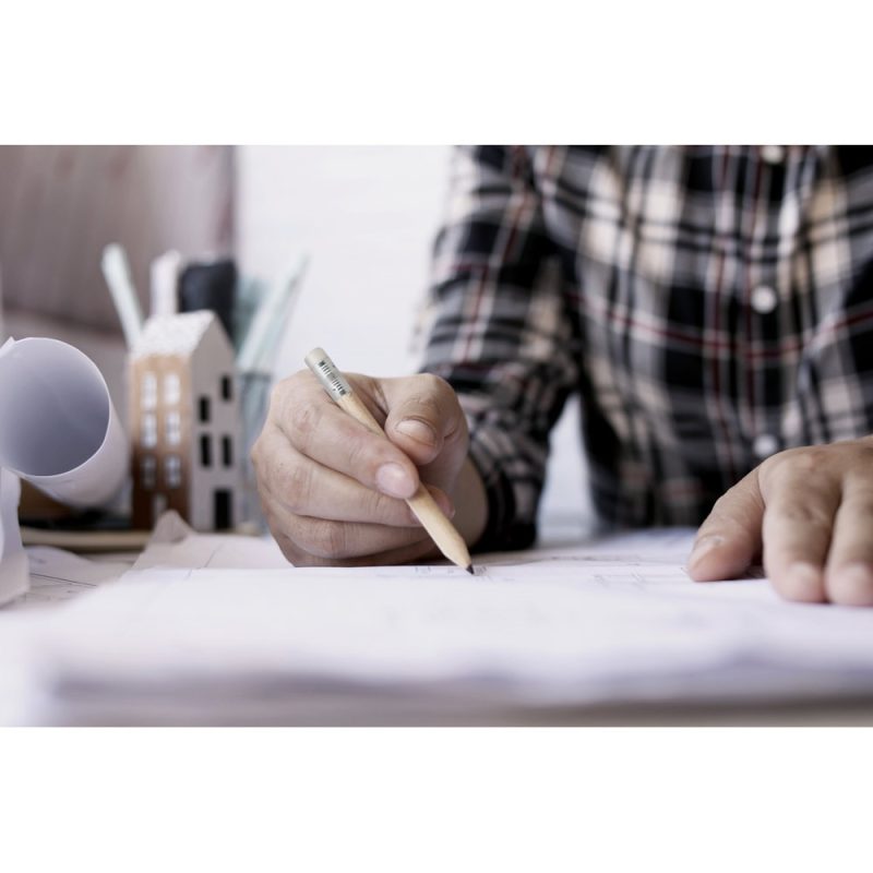 Person sketching architectural plans with pencil.