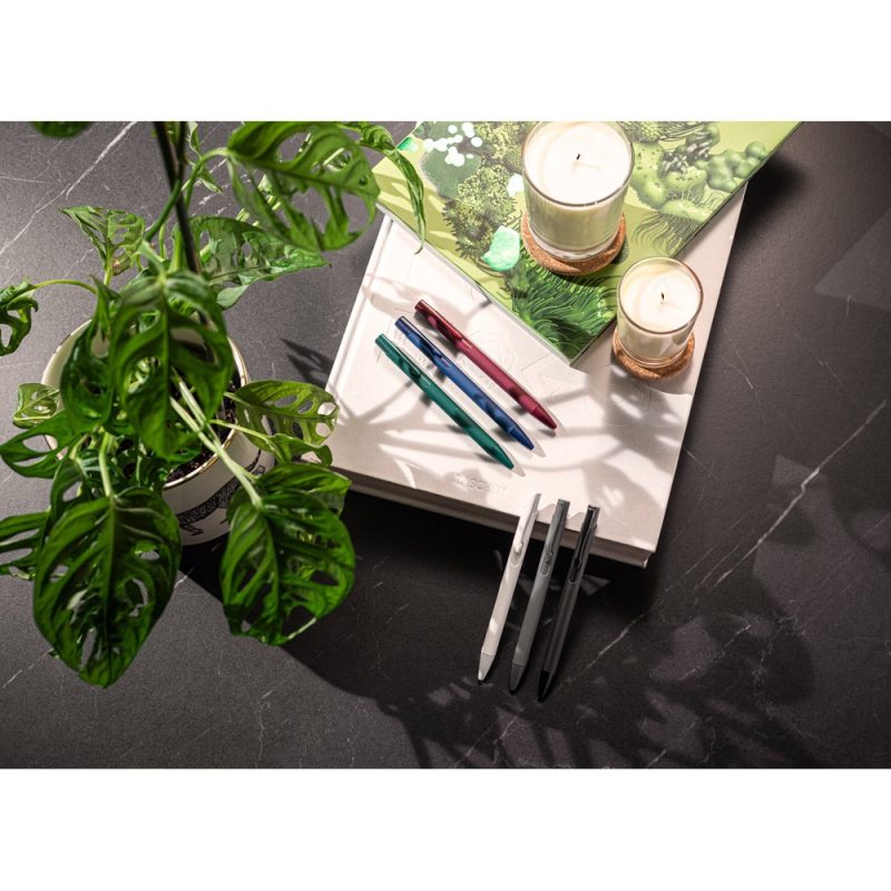 Pens, candles and plants on a desk.