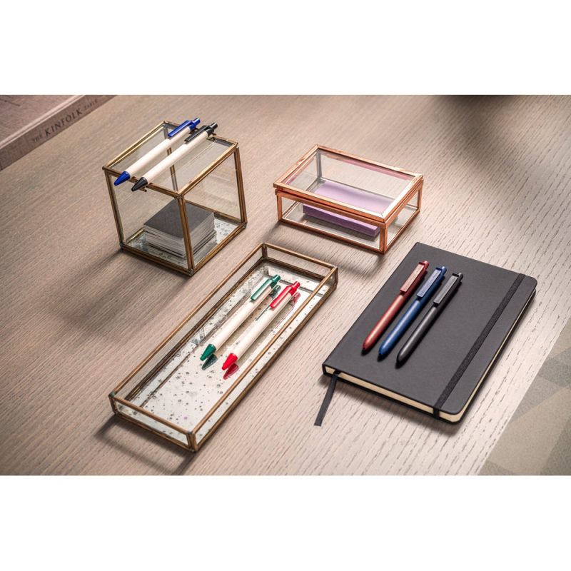 Desk with pens, notebook, and glass organisers.