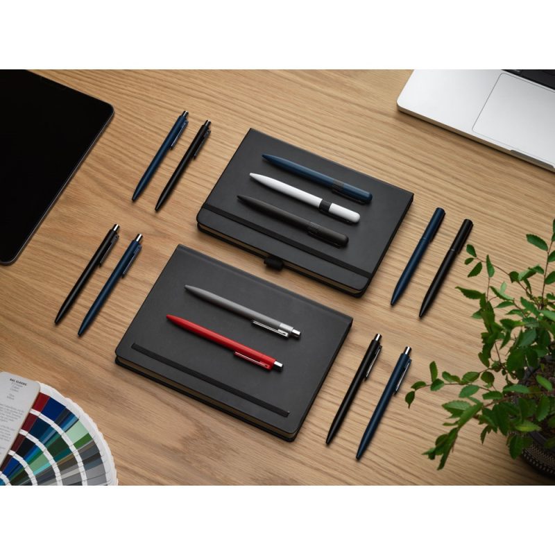 Notebooks and pens on wooden desk.