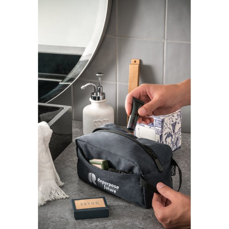 Hand reaches into travel toiletry bag on bathroom counter.