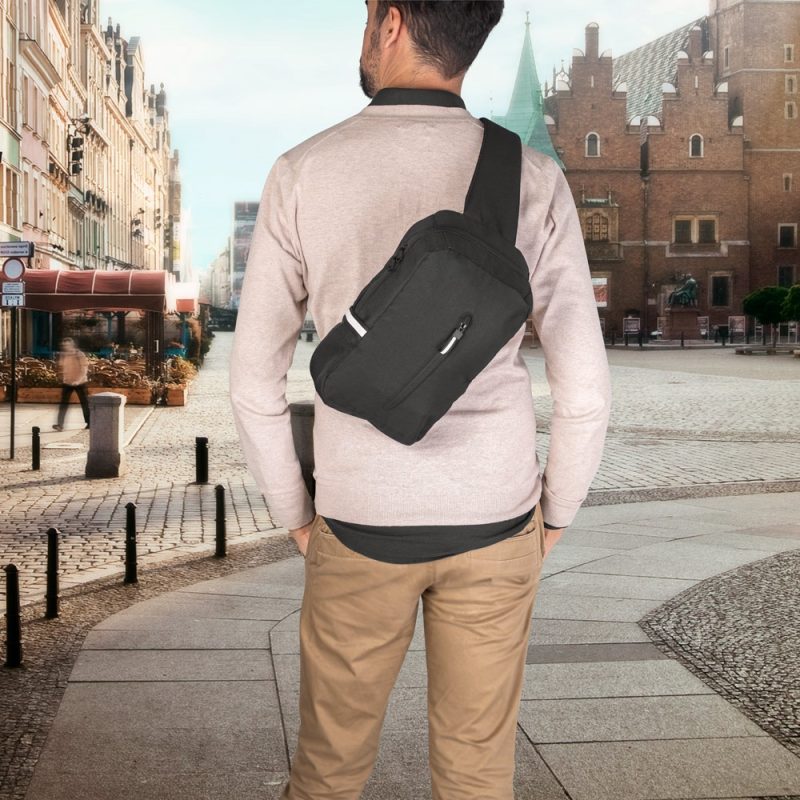 Man with black sling bag in city square.