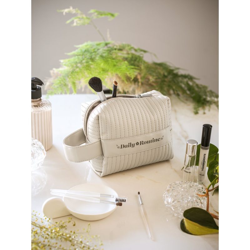 Cosmetic bag with makeup brushes on a table.