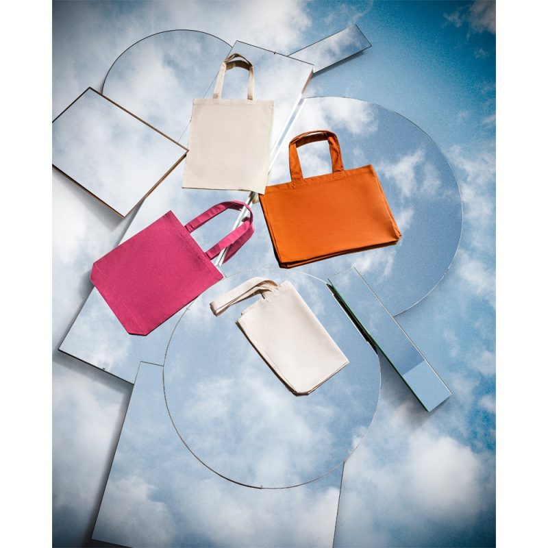 Colourful tote bags on sky reflection background.