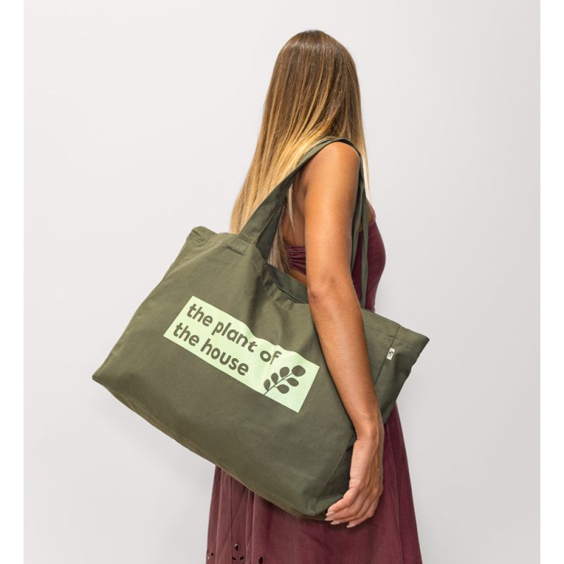 Woman carrying large green tote bag with text