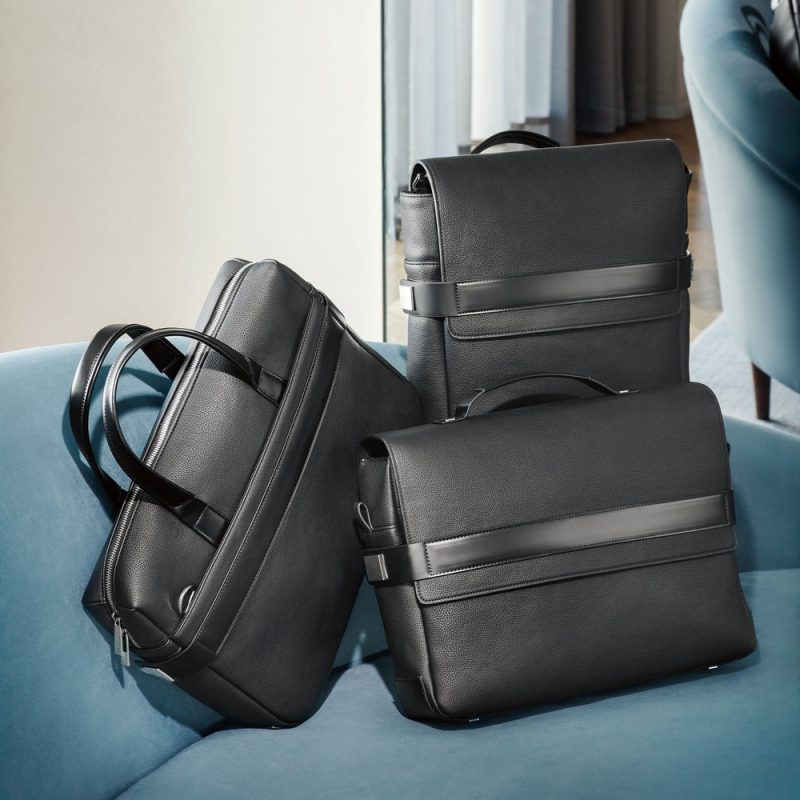 Three black leather bags on a blue sofa.