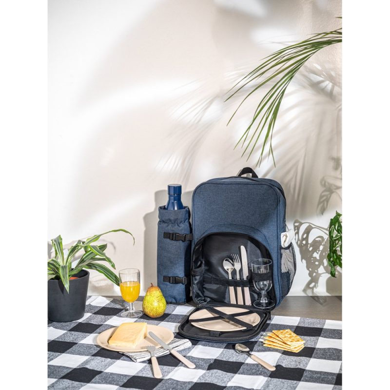 Picnic backpack with plates and cutlery on table.