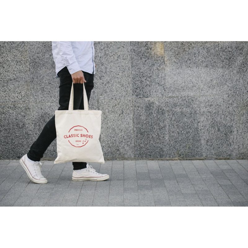 Person walking with tote bag on stone path.