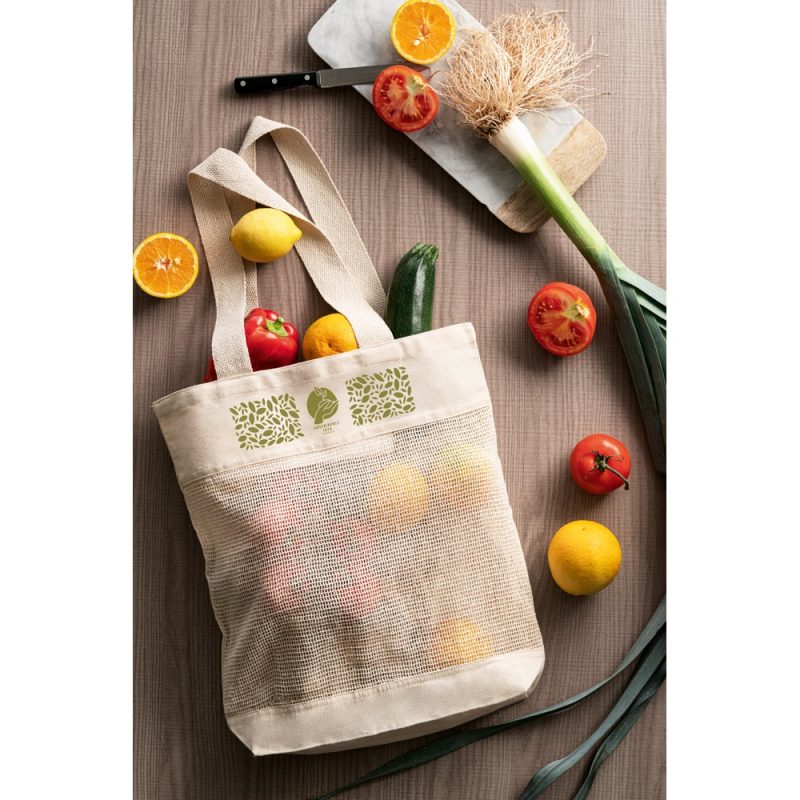 Reusable bag with fresh fruits and vegetables on table.