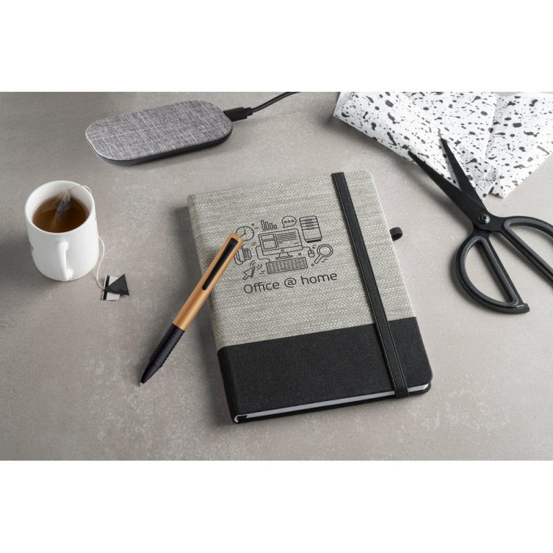 Office supplies on desk with notebook and tea.