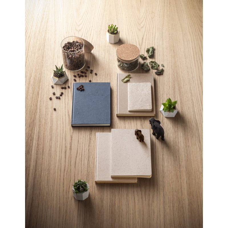 Notebooks with coffee beans and plants on wooden table.