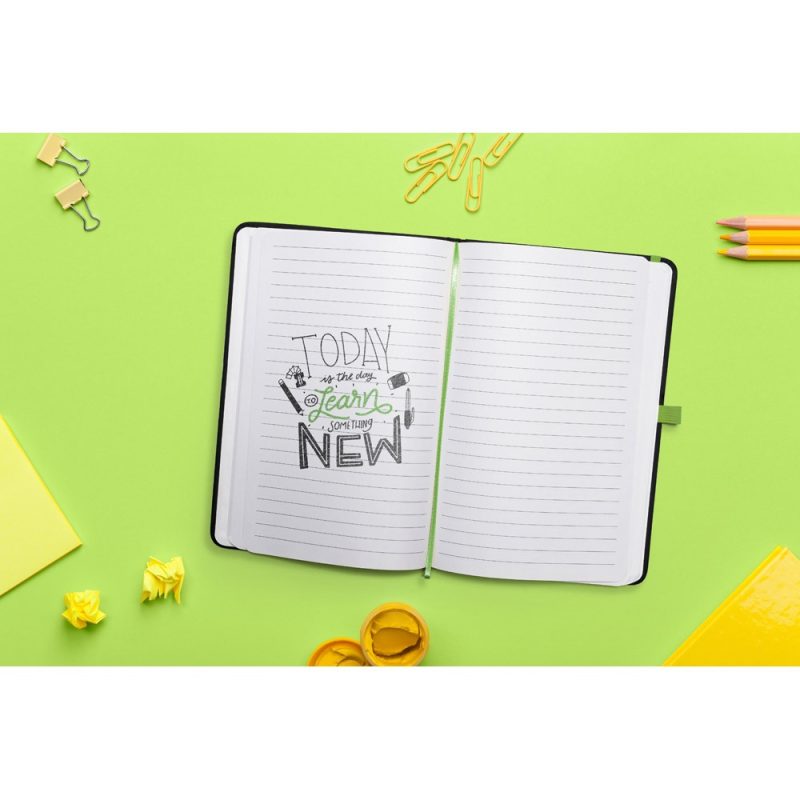 Open notebook on green background with pencils.