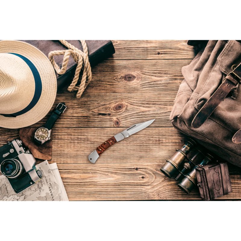 Travel items on wooden table, including knife.