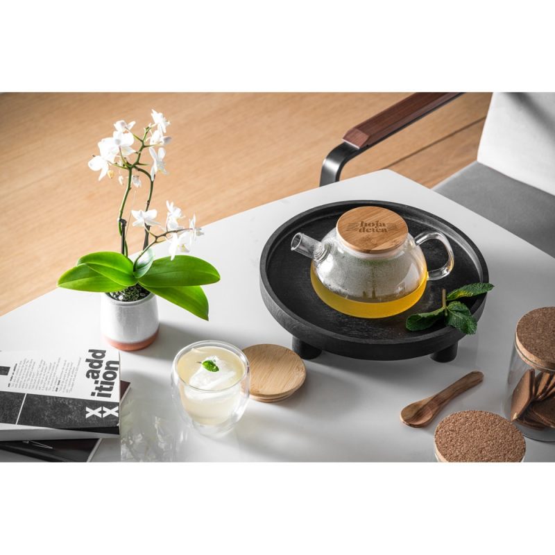 Glass teapot with tea on table, orchid beside.