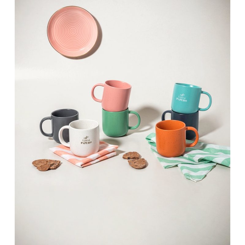 Colourful mugs and plates on a table with cookies.