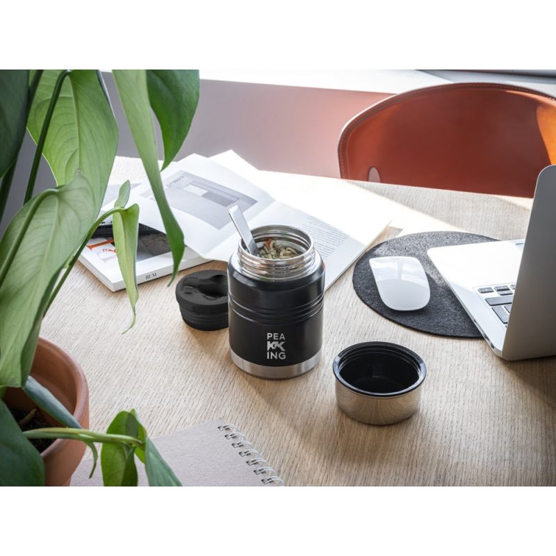 Thermos with lunch on desk near laptop and books.