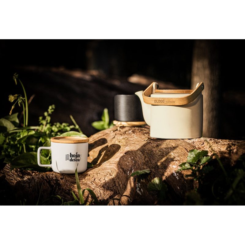 Ceramic teapot and mug on tree stump outdoors.