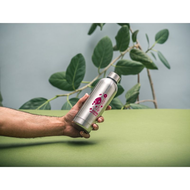 Hand holding silver bottle with colourful design.
