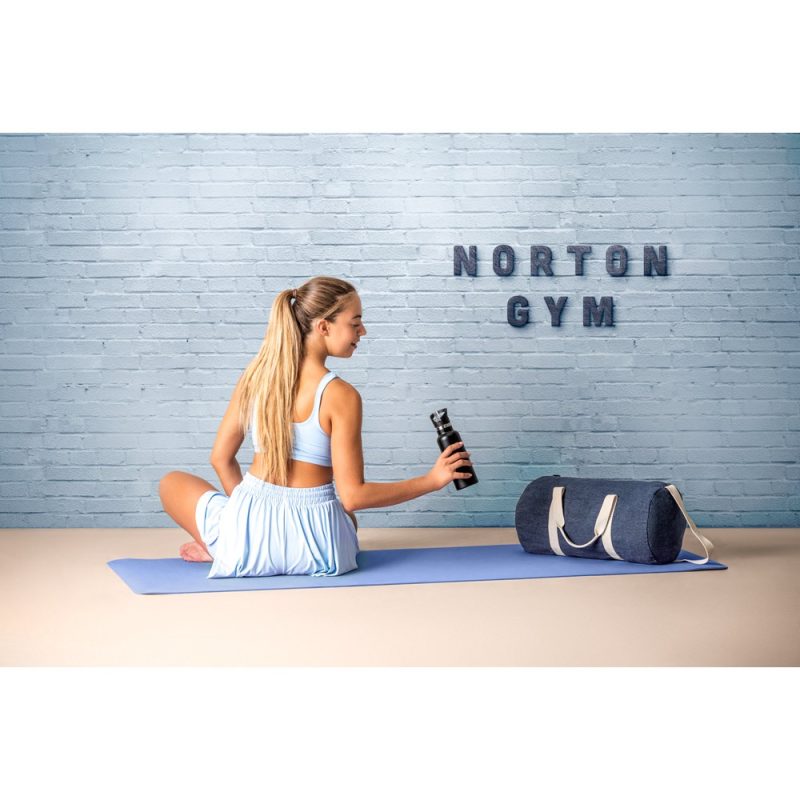 Woman in gym with yoga mat and bottle.