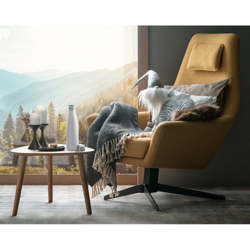 Cozy chair with throw blanket by mountain window.