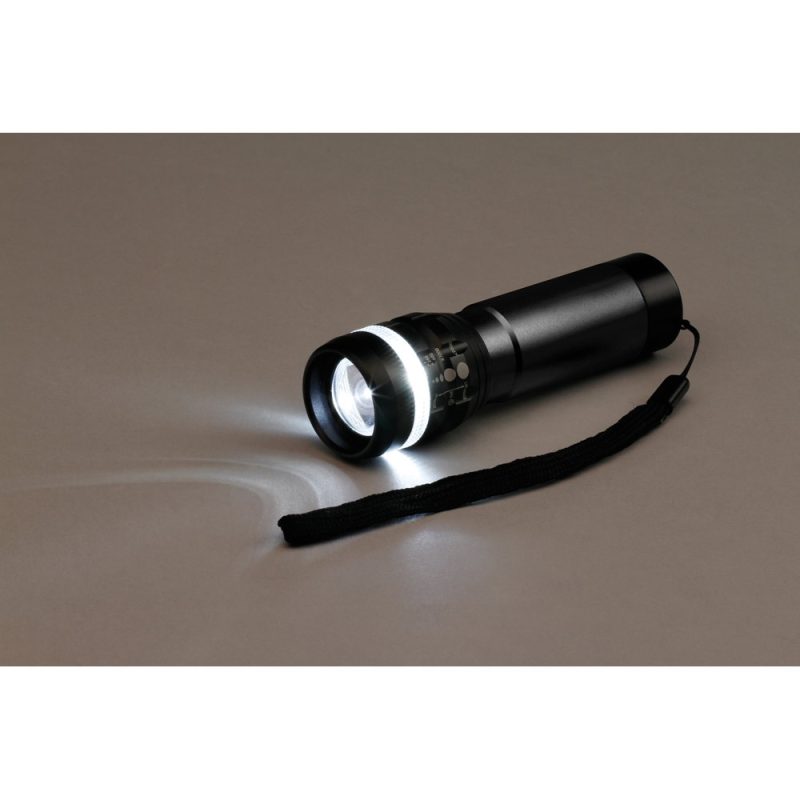 Black LED torch with wrist strap on table.
