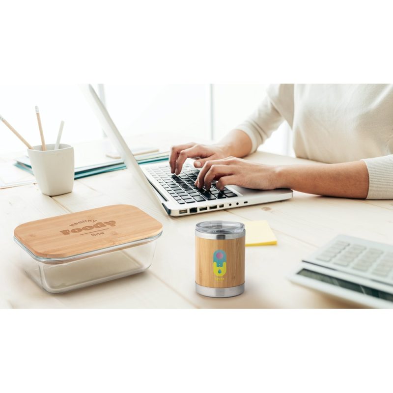 Person using laptop with bamboo lunchbox and grinder