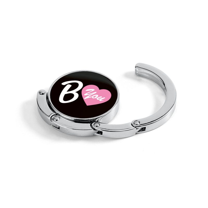 Metal bag hanger with 'B You' heart design.